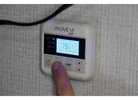 White plastic advent air thermostat with digital display showing 79 degrees and control buttons for power, fan, and temperature adjustment.